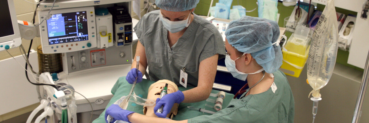 Deux étudiantes en salle d'opération manipulent des instruments au-dessus d'un mannequin intelligent.