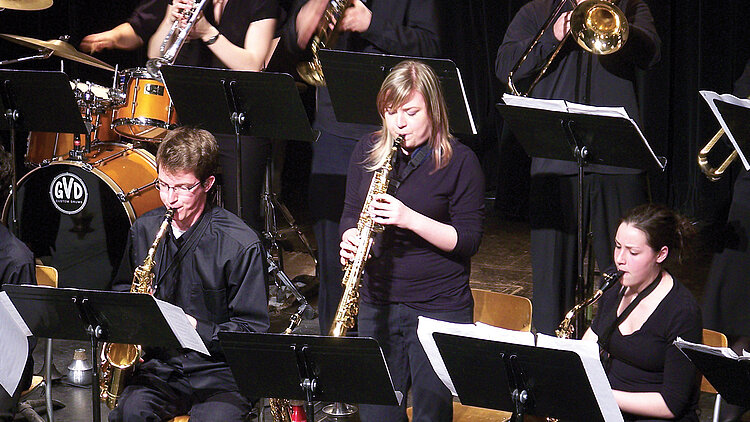 Une étudiante joue de son instrument au milieu d'un orchestre.